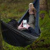 Man in the forest in black gray light hammock Alpin Loacker for outdoor hiking and camping, hammock with carabiners and pack sack